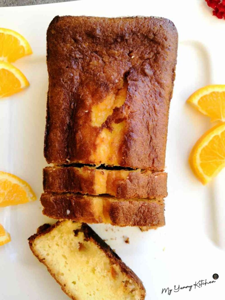 Gâteau à l'orange ultra moelleux servi sur une assiette blanche avec des tranches d'oranges